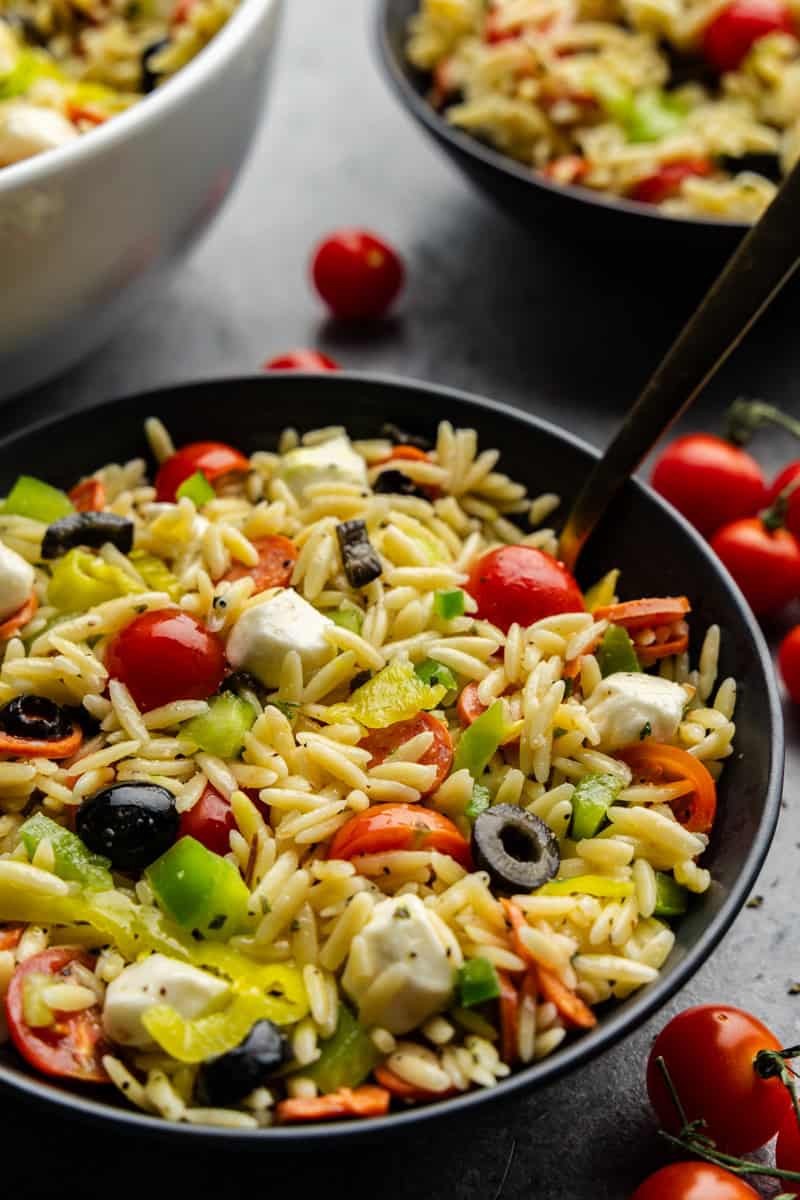 Ensalada de pasta orzo italiana en un tazón pequeño con una cuchara.