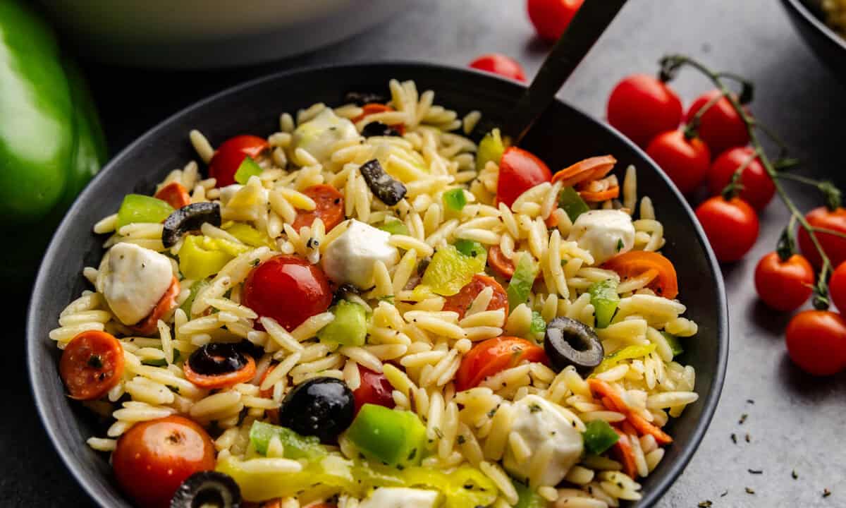 Italian orzo Pasta salad in a small bowl with a spoon in it.