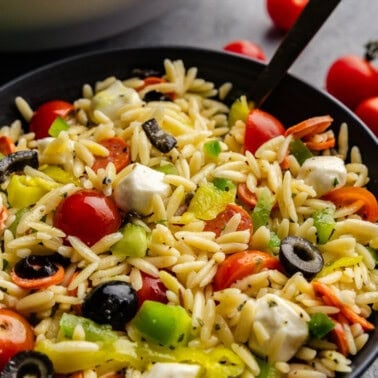Italian orzo Pasta salad in a small bowl with a spoon in it.