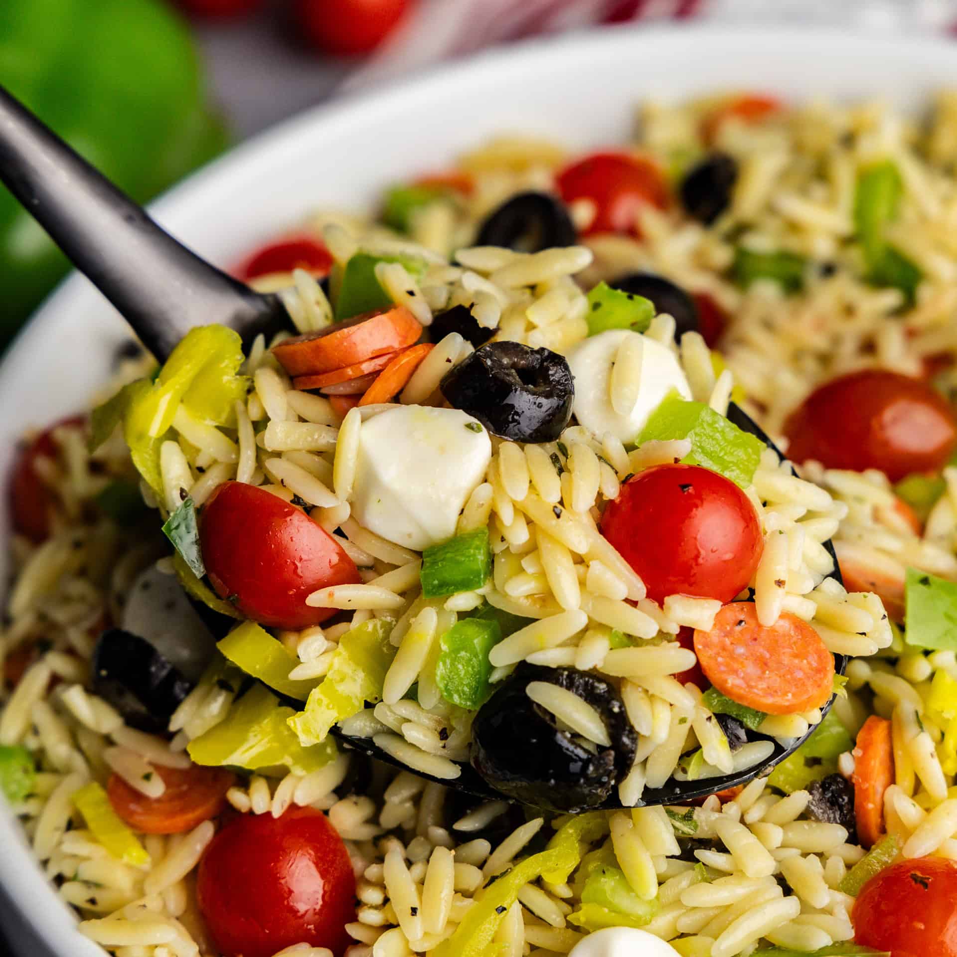 Italian orzo Pasta salad scooped up onto a serving spoon.