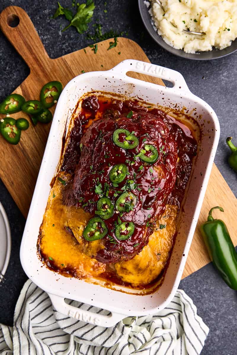 Overhead shot of Jalapeno Cheddar Stuffed Meatloaf in a roasting pan with ingredients surrounding it.