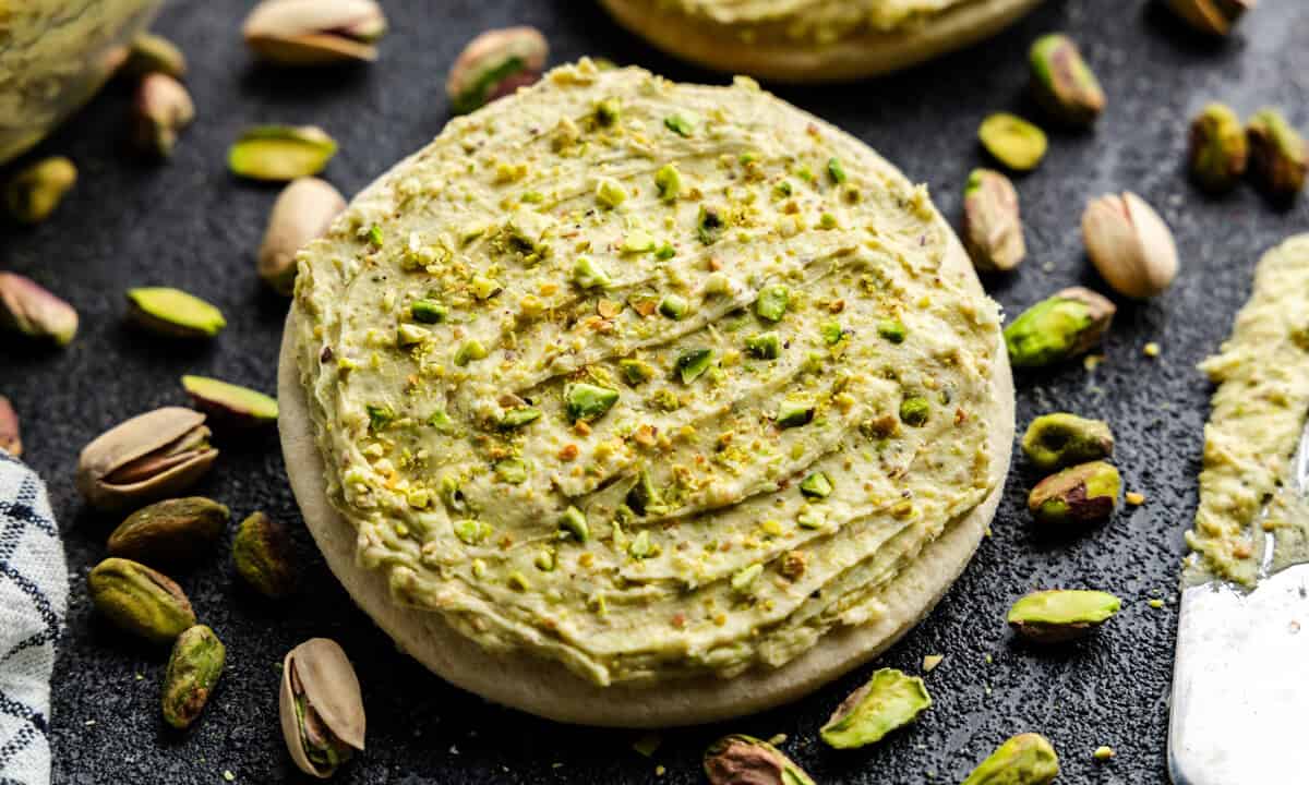 Closeup of Pistachio Buttercream Frosting on a cookie surrounded by pistachios.