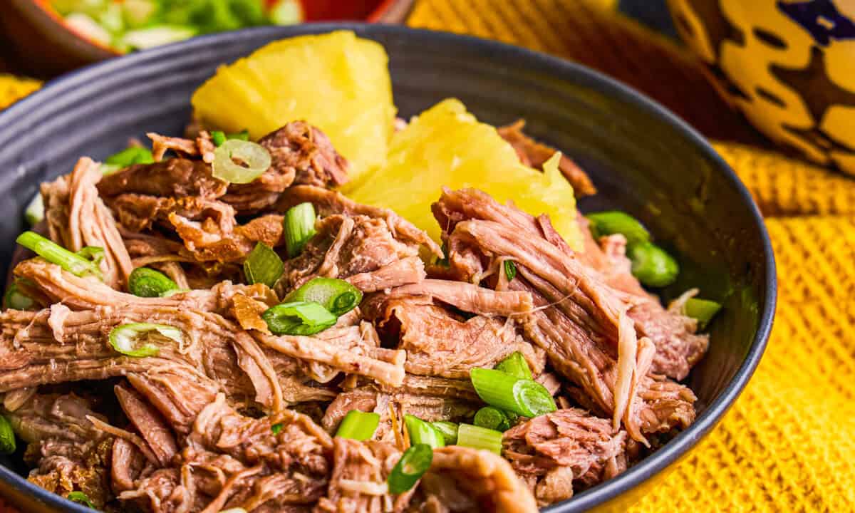 Slow Cooker Kalua Pork in a bowl with Pineapple and green onions.