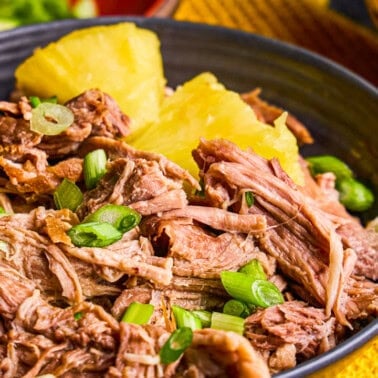 Slow Cooker Kalua Pork in a bowl with Pineapple and green onions.