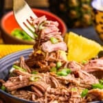 Slow Cooker Kalua Pork on a fork with green onions.