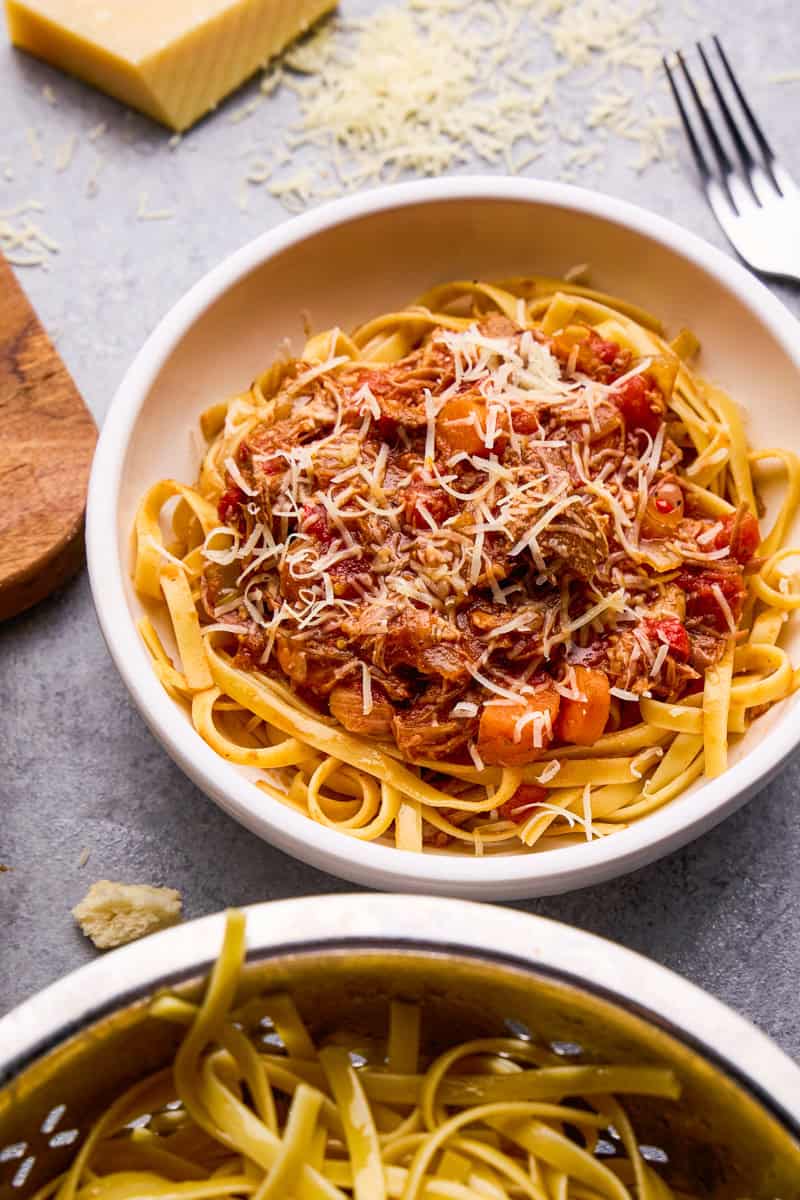 Slow Cooker Pork Ragu over noodles in a bowl topped with parmesan cheese.