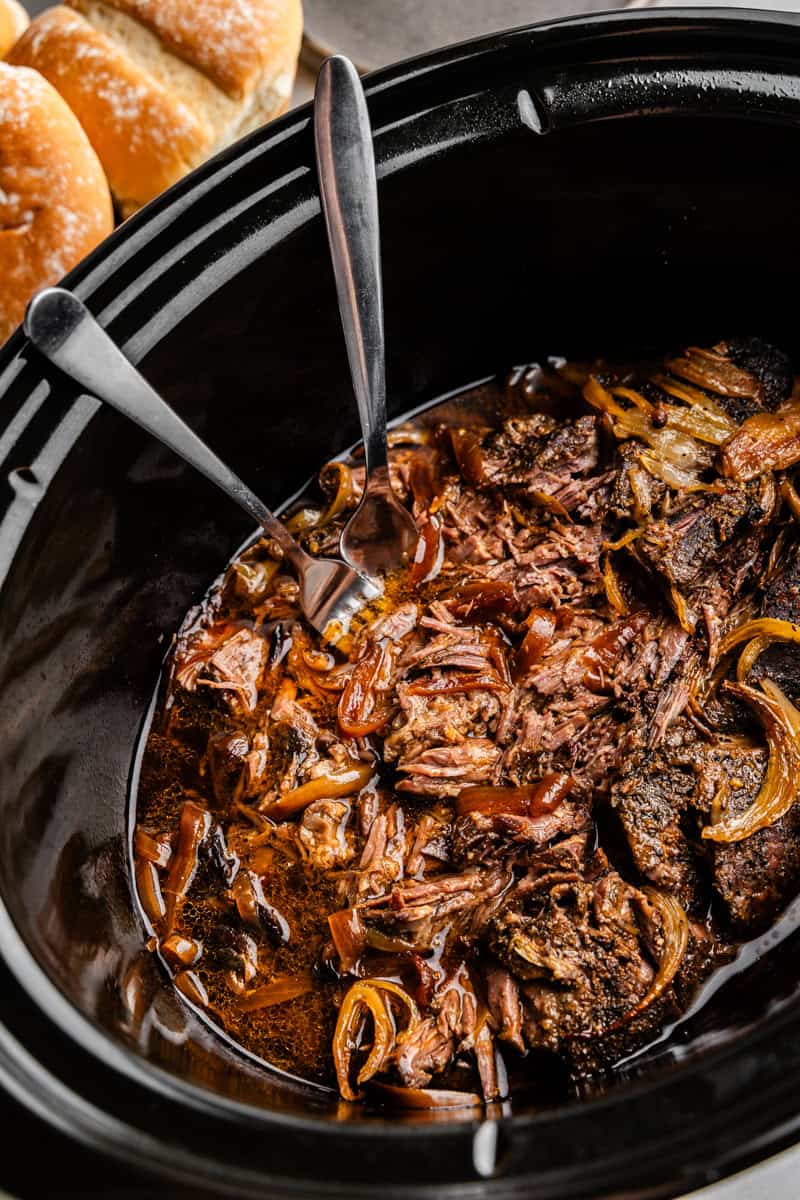 Primer plano de una carne rallada en una olla de cocción lenta.