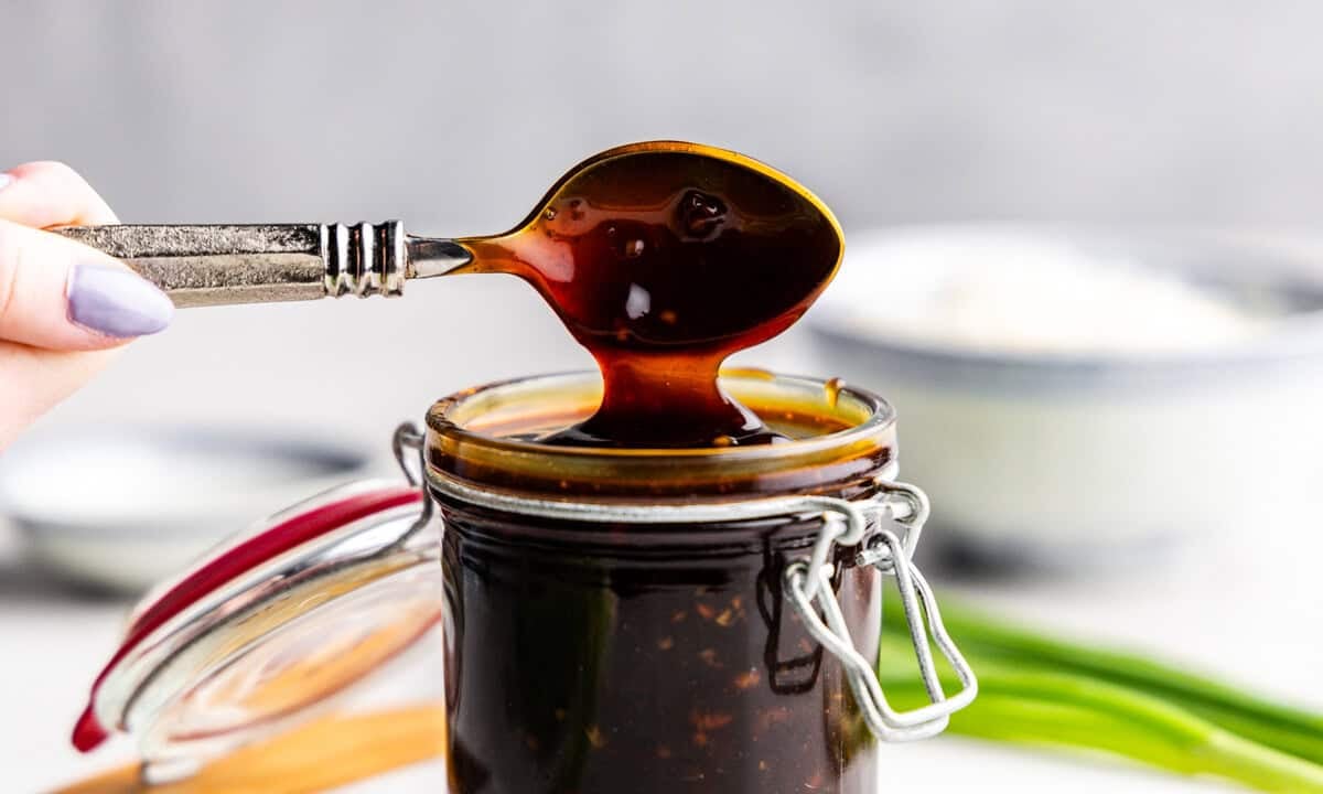 Closeup of teriyaki sauce being lifted with spoon out of glass.