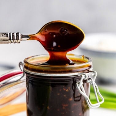 Closeup of teriyaki sauce being lifted with spoon out of glass.