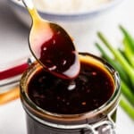 Closeup of teriyaki sauce being lifted with spoon out of glass.