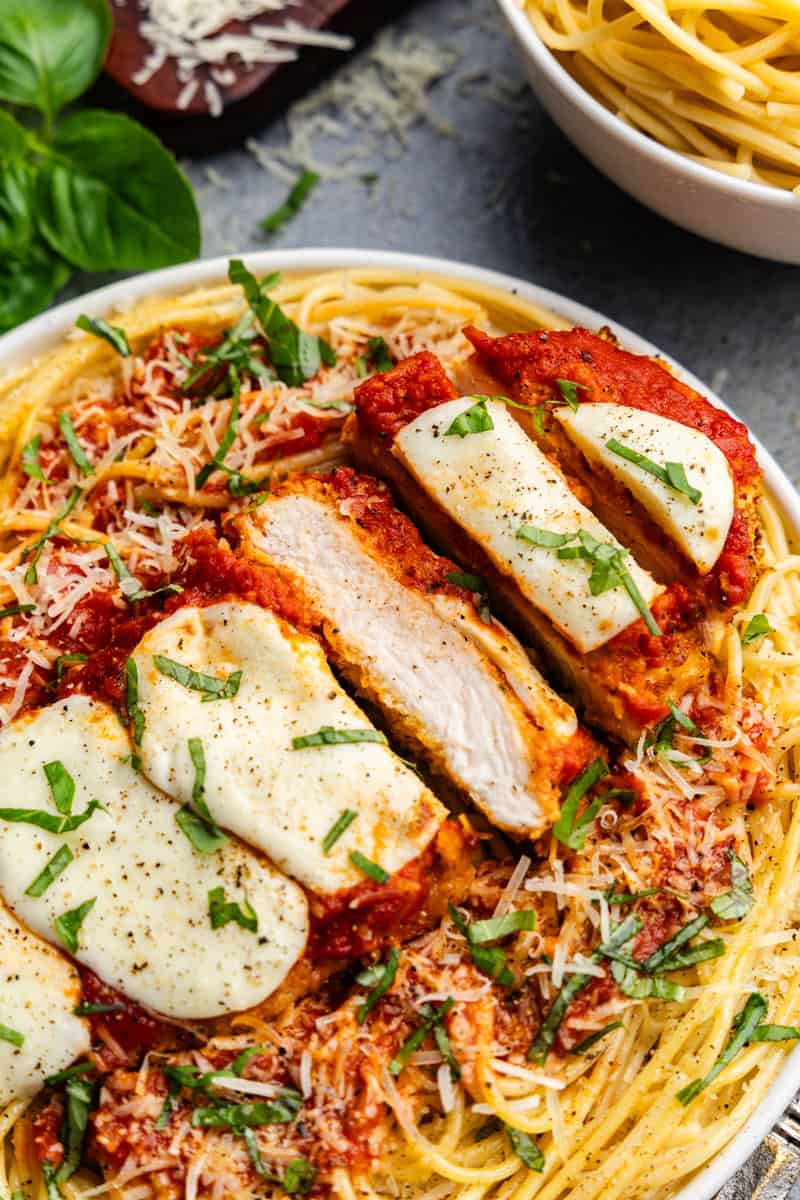 Closeup of chicken parmesan sliced on a plate of pasta.