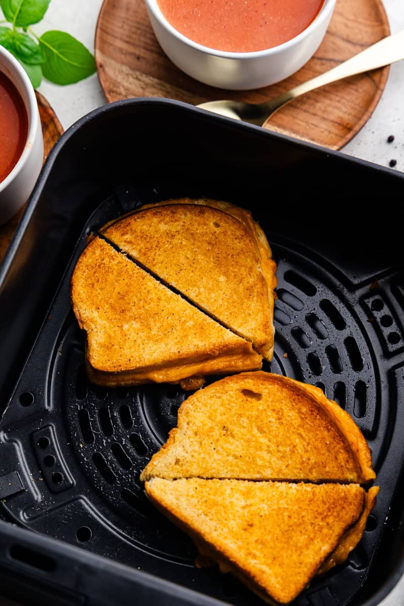 Closeup of two Grilled cheese sandwiches split in half in the air fryer.