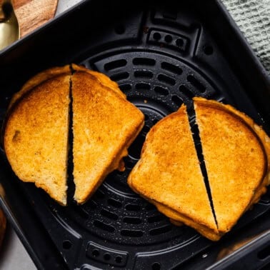 Closeup of two Grilled cheese sandwiches split in half in the air fryer.