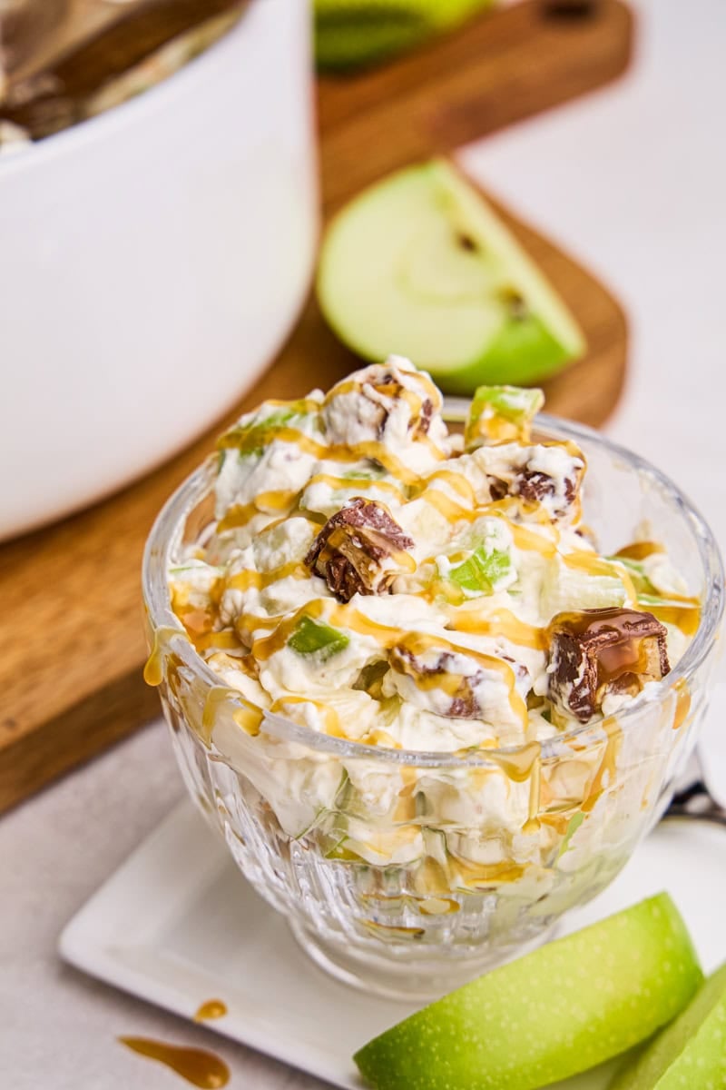Apple Snickers Salad in a glass cup with caramel drizzle on top.