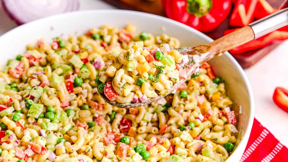 Best Macaroni Salad in a large bowl with a wooden spoonful hovering above.