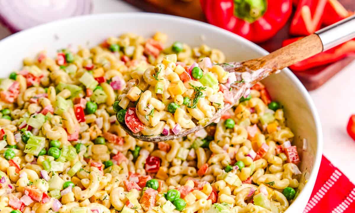 Best Macaroni Salad in a large bowl with a wooden spoonful hovering above.