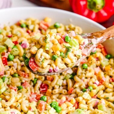 Best Macaroni Salad in a large bowl with a wooden spoonful hovering above.