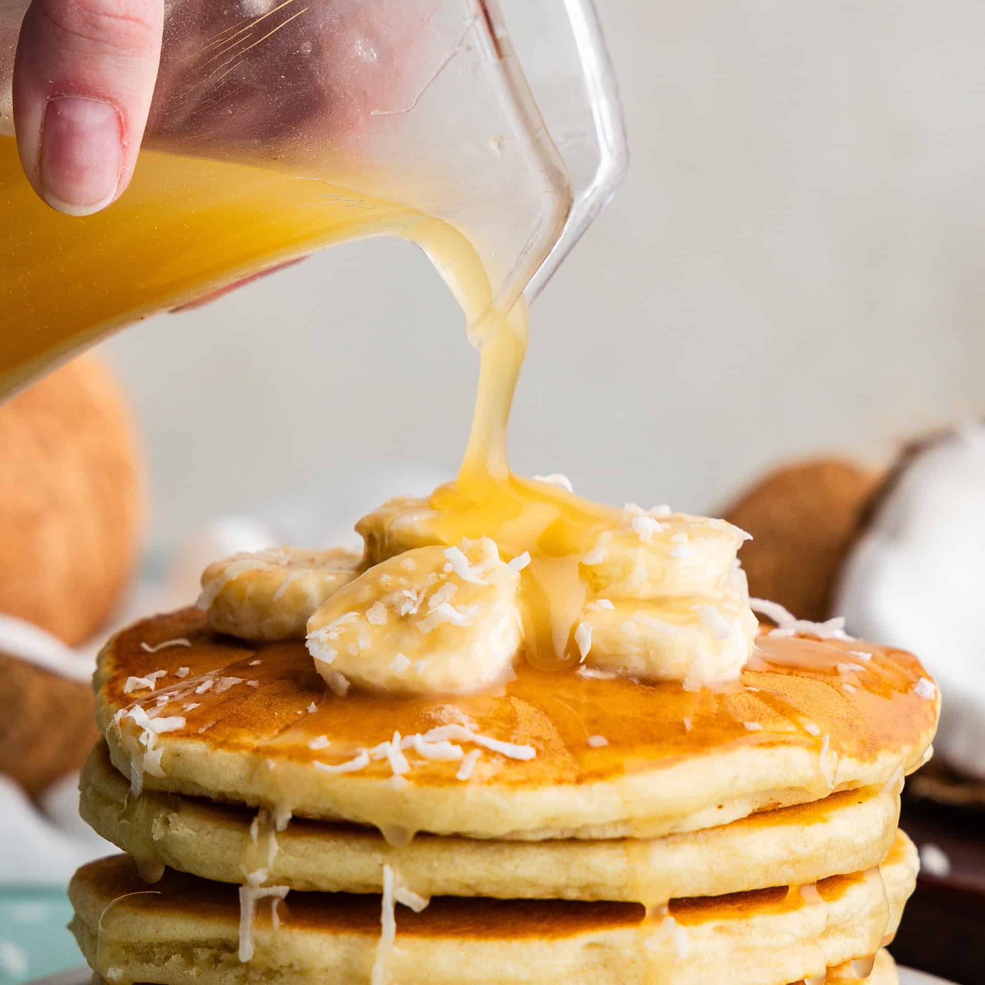 Coconut Syrup being poured on pancakes.