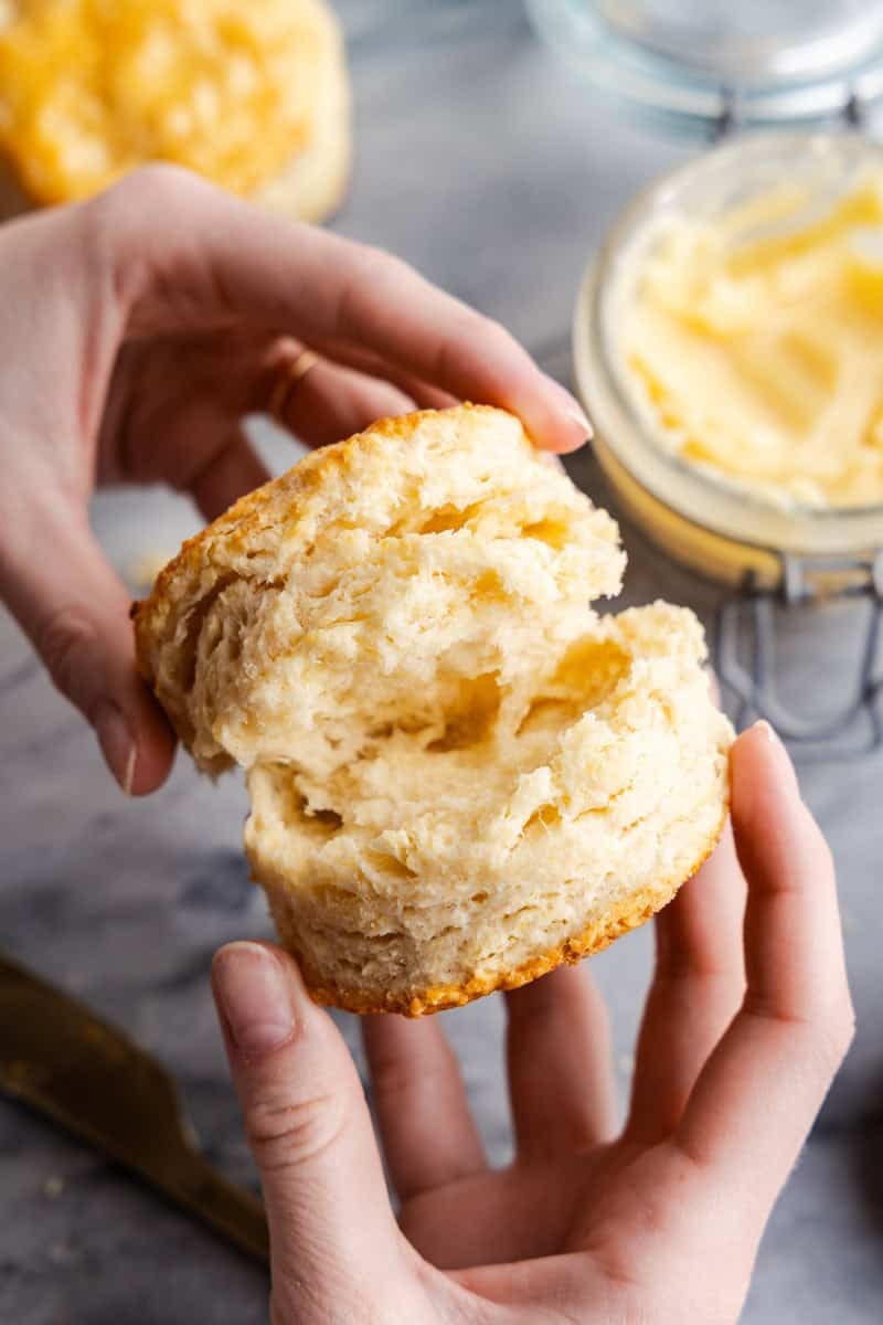Hands pulling a flaky biscuit apart.