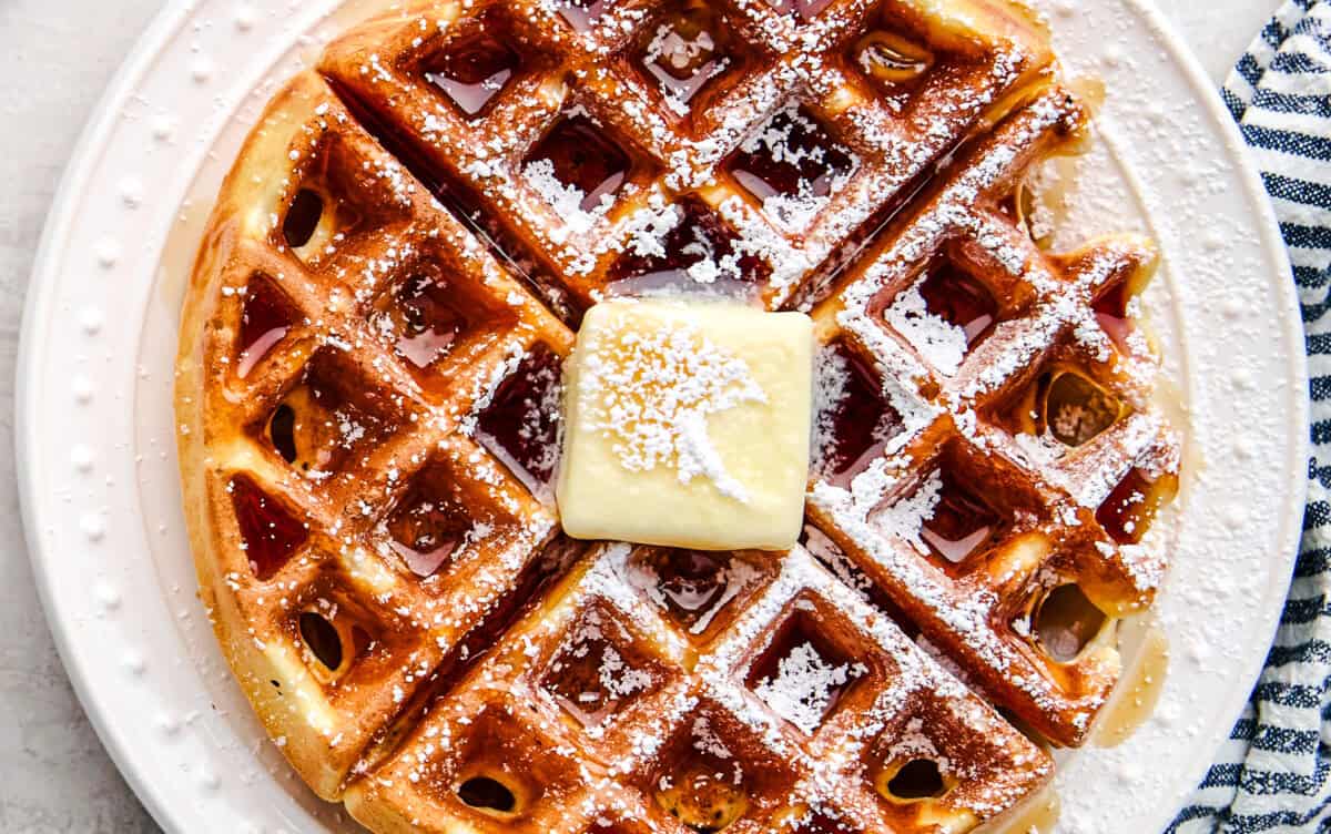 Overhead Greek Yogurt Waffle with butter, syrup and powdered sugar.