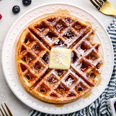 Overhead Greek Yogurt Waffle with butter, syrup and powdered sugar.