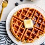 An overhead image of a Greek Yogurt Waffle with a pat of butter and syrup drizzled over top.