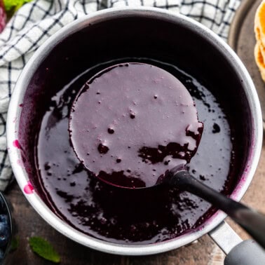 Pot of blueberry syrup with a ladleful in it.