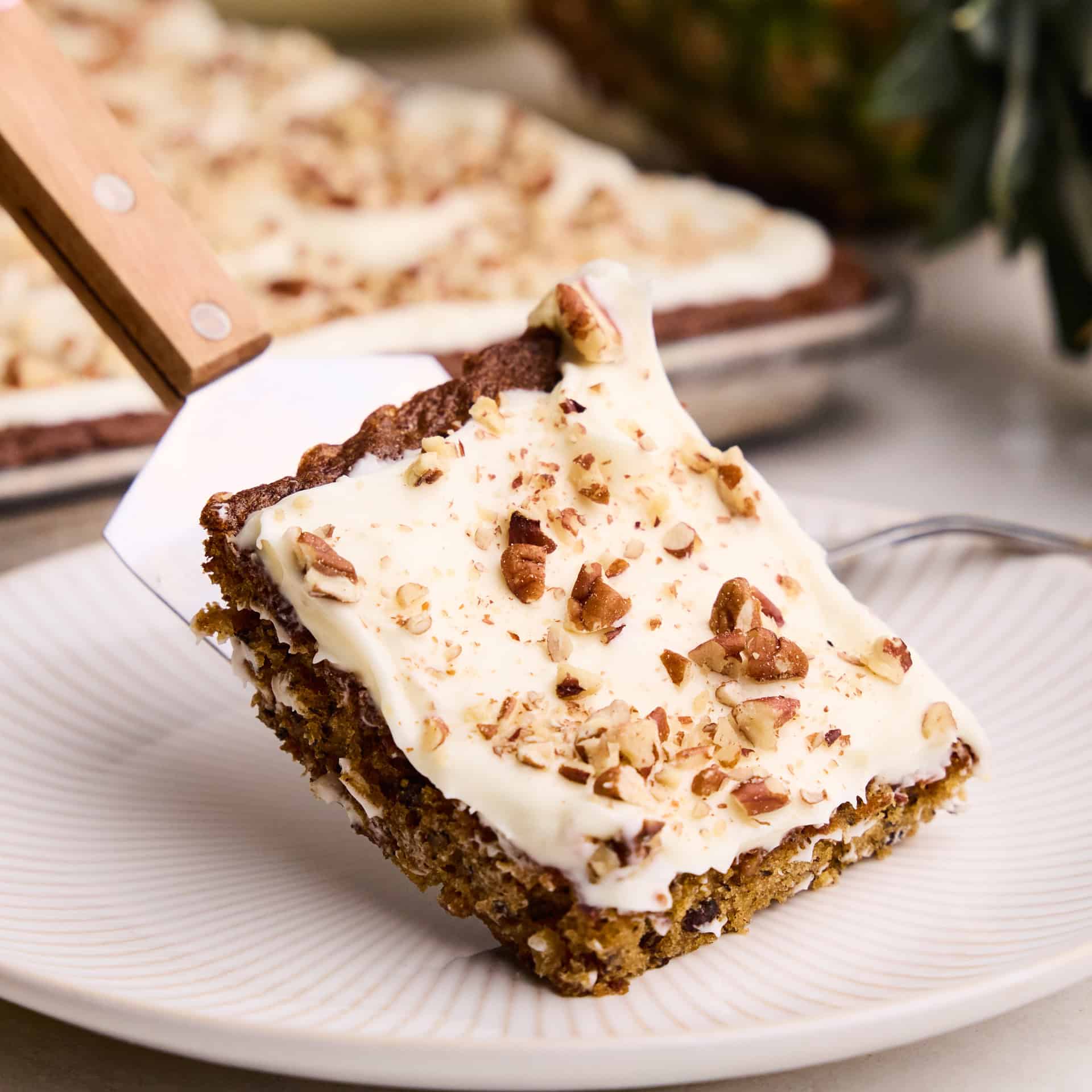 A piece of Hummingbird Sheet Cake being put onto a plate.
