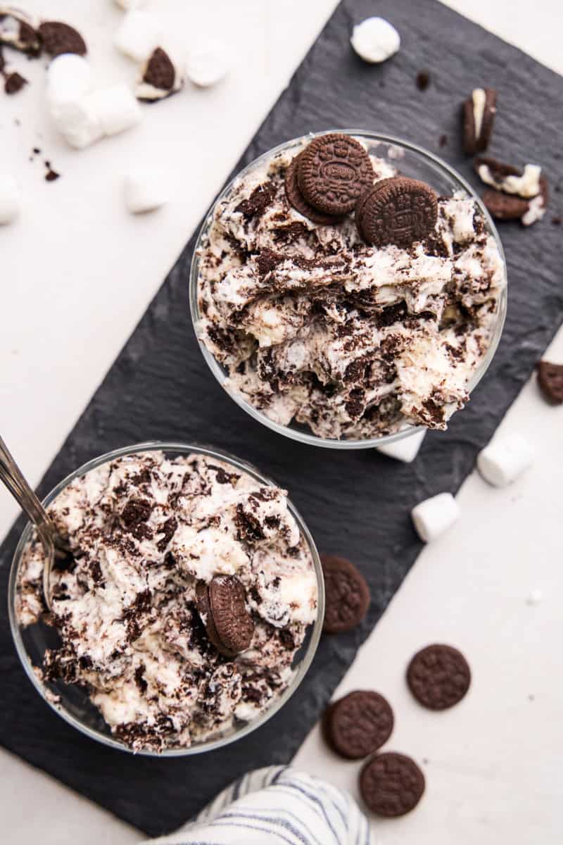 Overhead image of Oreo Fluff in 2 parfait cups with marshmallows and chocolate sandwich cookies scattered around.