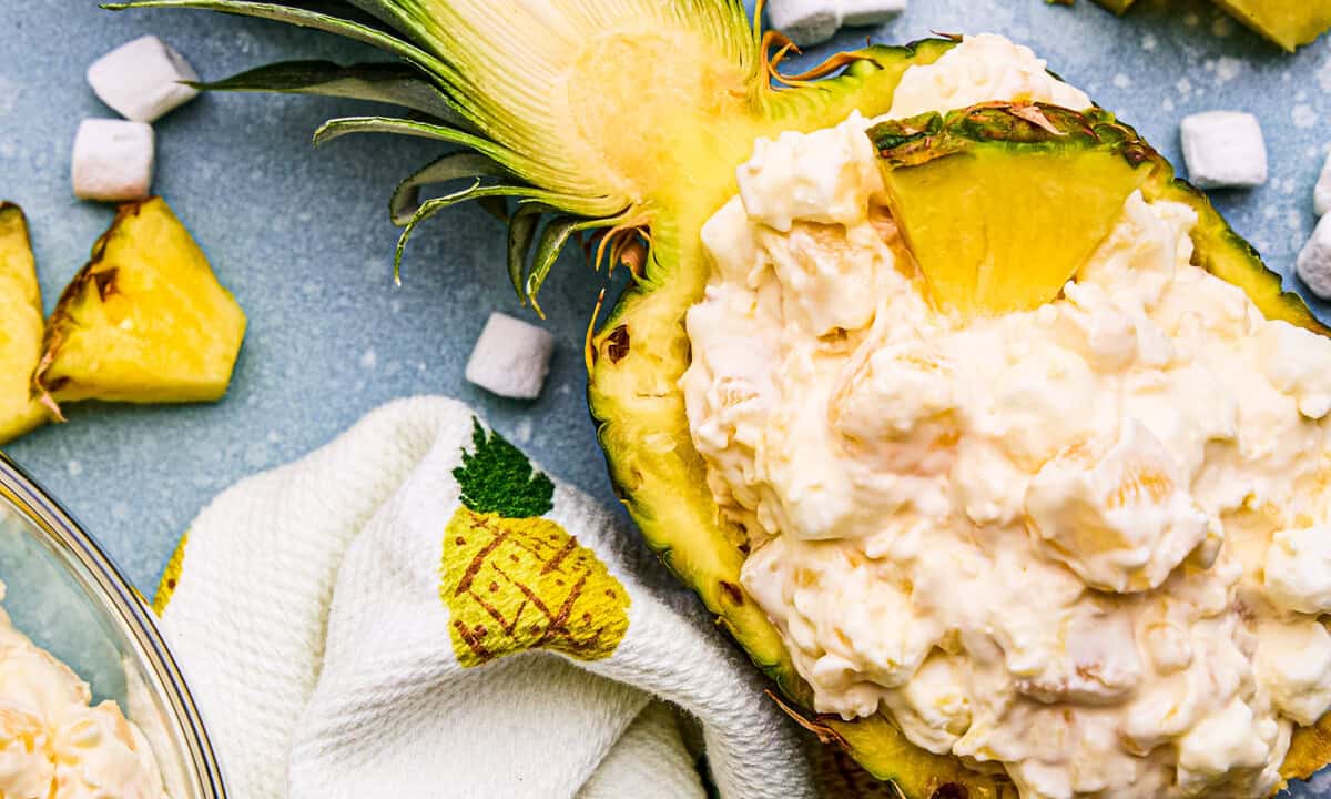 Pineapple Fluff in a hollowed out pineapple with marshmallows and pineapple chunks around.