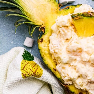 Pineapple Fluff in a hollowed out pineapple with marshmallows and pineapple chunks around.