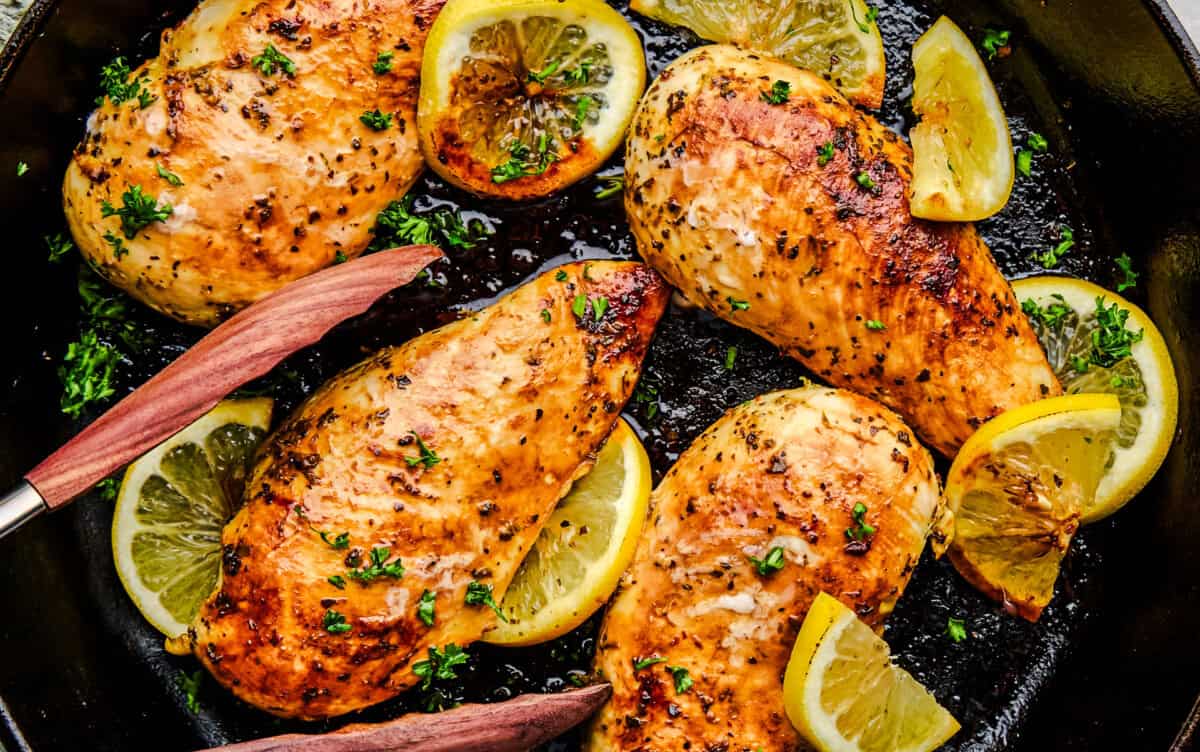An overhead image of Quick and Easy Lemon Chicken in a cast iron pan with tongs.