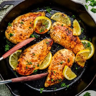 An overhead image of Quick and Easy Lemon Chicken in a cast iron pan with tongs.