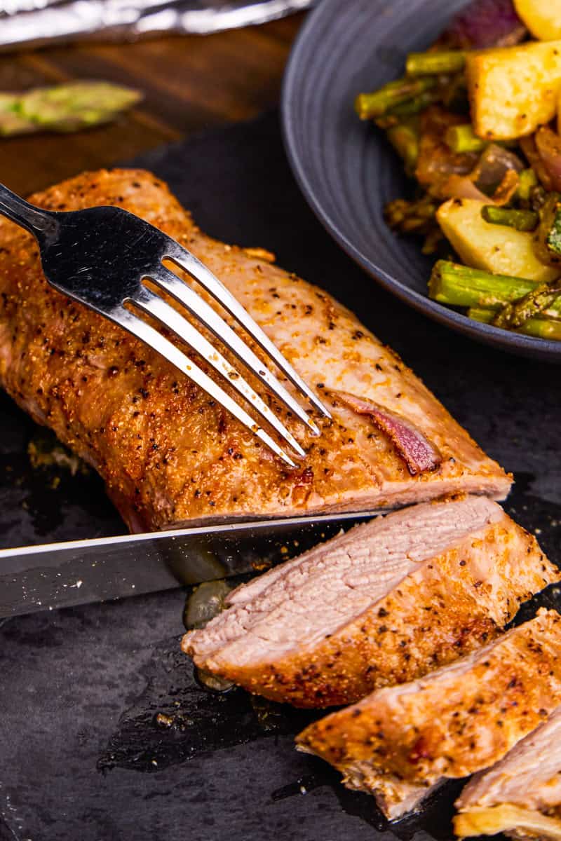 Sheet Pan Pork Tenderloin being sliced & Veggies.