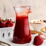 Closeup of a pitcher of strawberry syrup.