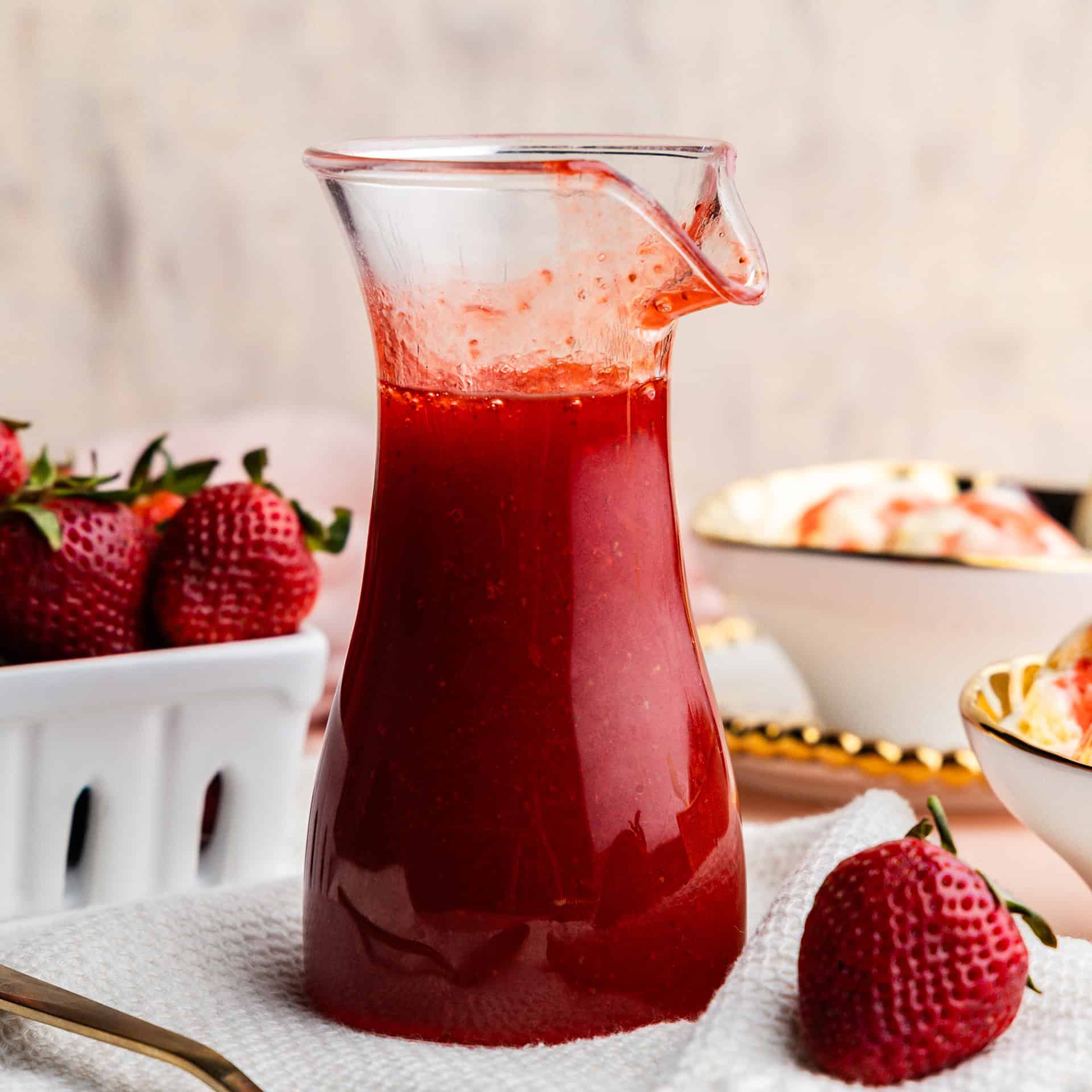 Closeup of a pitcher of strawberry syrup.