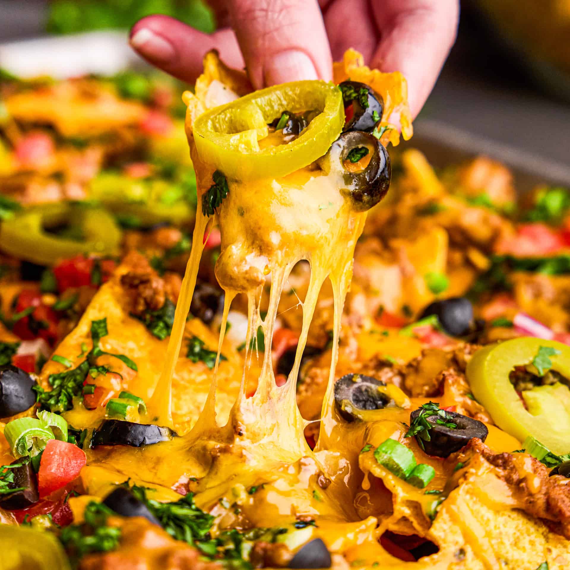 Ultimate Nacho Recipe chip with cheese pull.