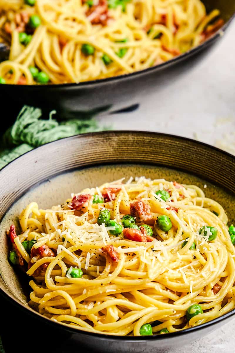 American Carbonara in a bowl topped with fresh grated parmesan cheese.