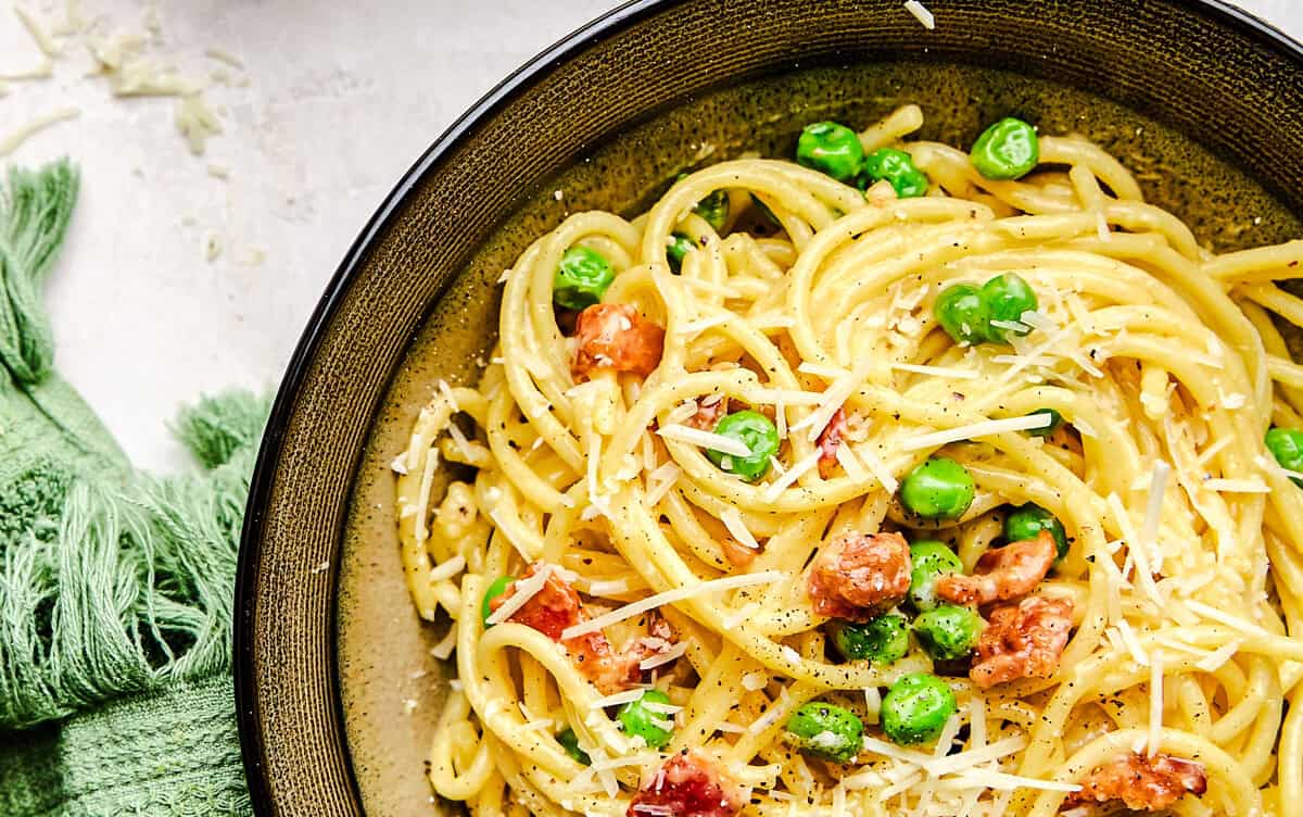 American Carbonara in a bowl topped with fresh grated parmesan cheese.