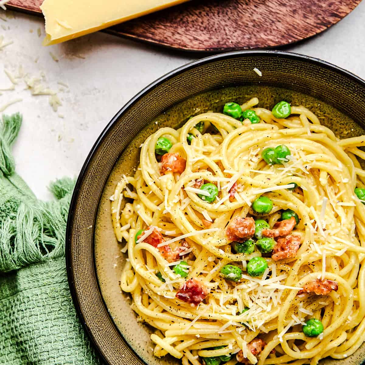 American Carbonara in a bowl topped with fresh grated parmesan cheese.