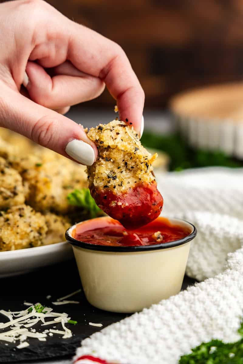 Closeup of chicken nugget being dipped in ketchup.