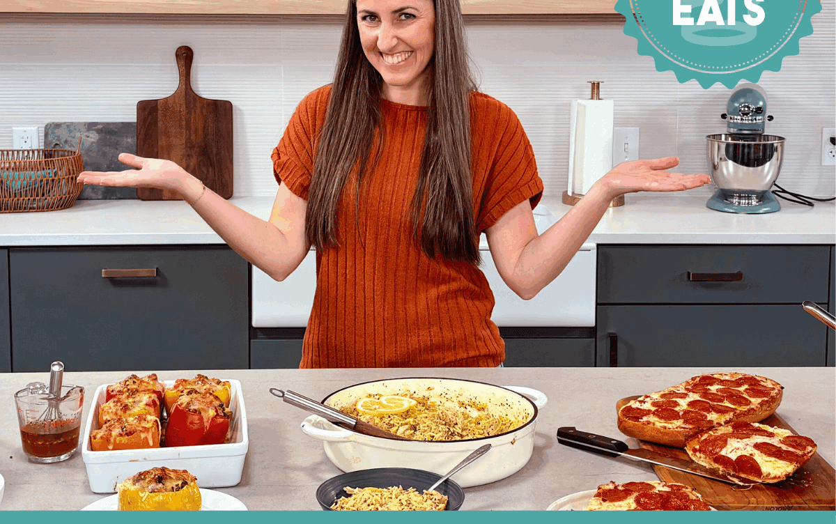 A photo of Rachel in The Stay At Home Chef Kitchen with the meals from Week 3 of the Cheap Eats Meal plan on display on the kitchen counter.