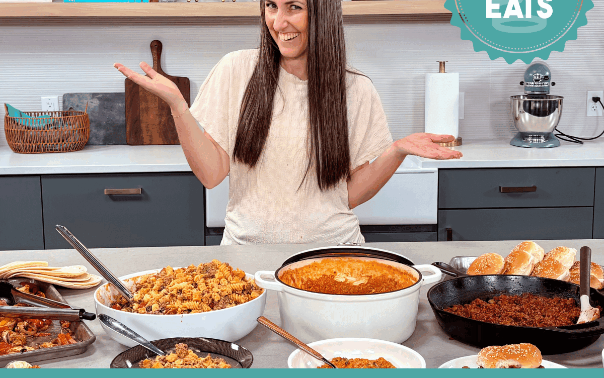 A photo of Rachel in The Stay At Home Chef Kitchen with the meals from Week 4 of the Cheap Eats Meal plan on display on the kitchen counter.