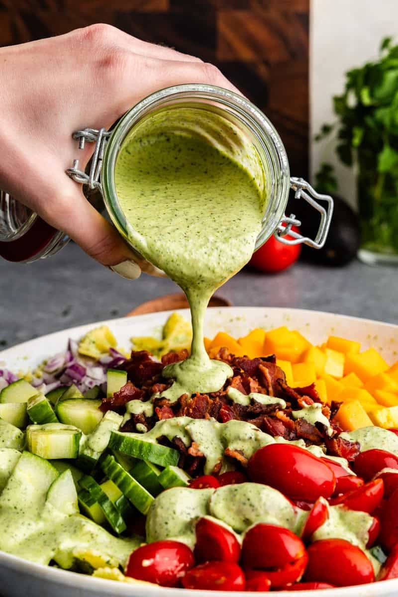 Cilantro ranch being poured onto the pasta salad.