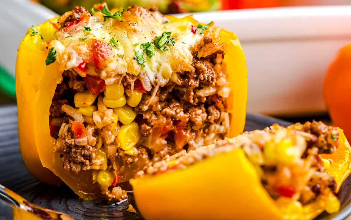 A cheese topped stuffed yellow bell pepper sliced in half revealing the filling. Easy Stuffed Bell Peppers.