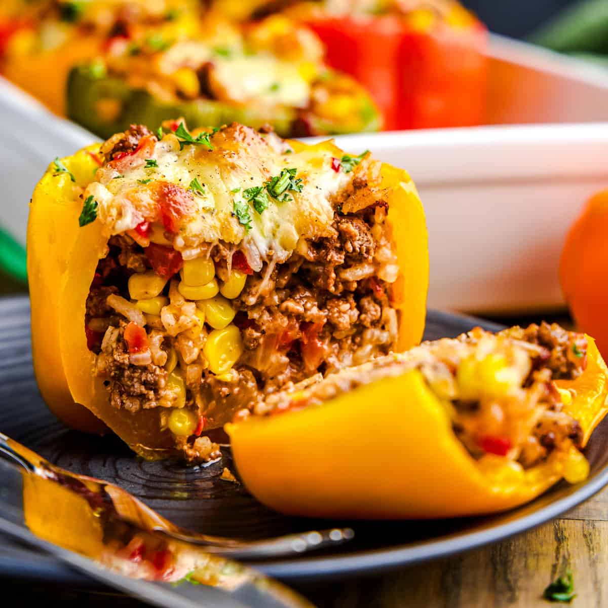A cheese topped stuffed yellow bell pepper sliced in half revealing the filling. Easy Stuffed Bell Peppers.