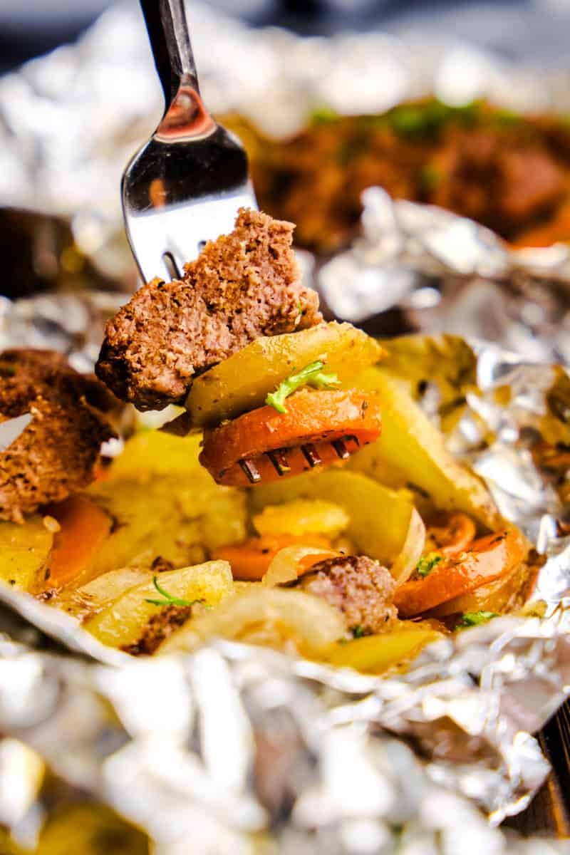 A forkful of meat, potato and carrot above Hobo Foil Packets.