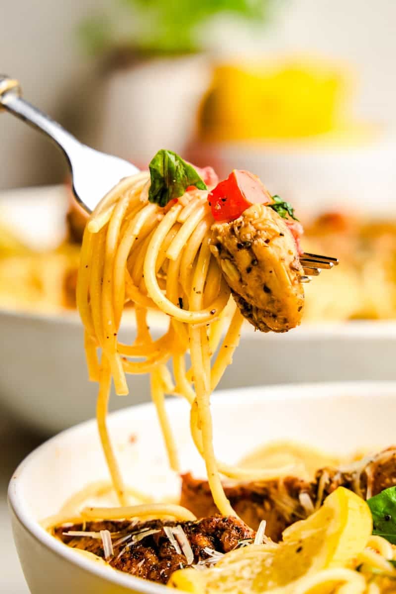A forkful of Lemon Herb Chicken Spaghetti with tomatoes and basil.