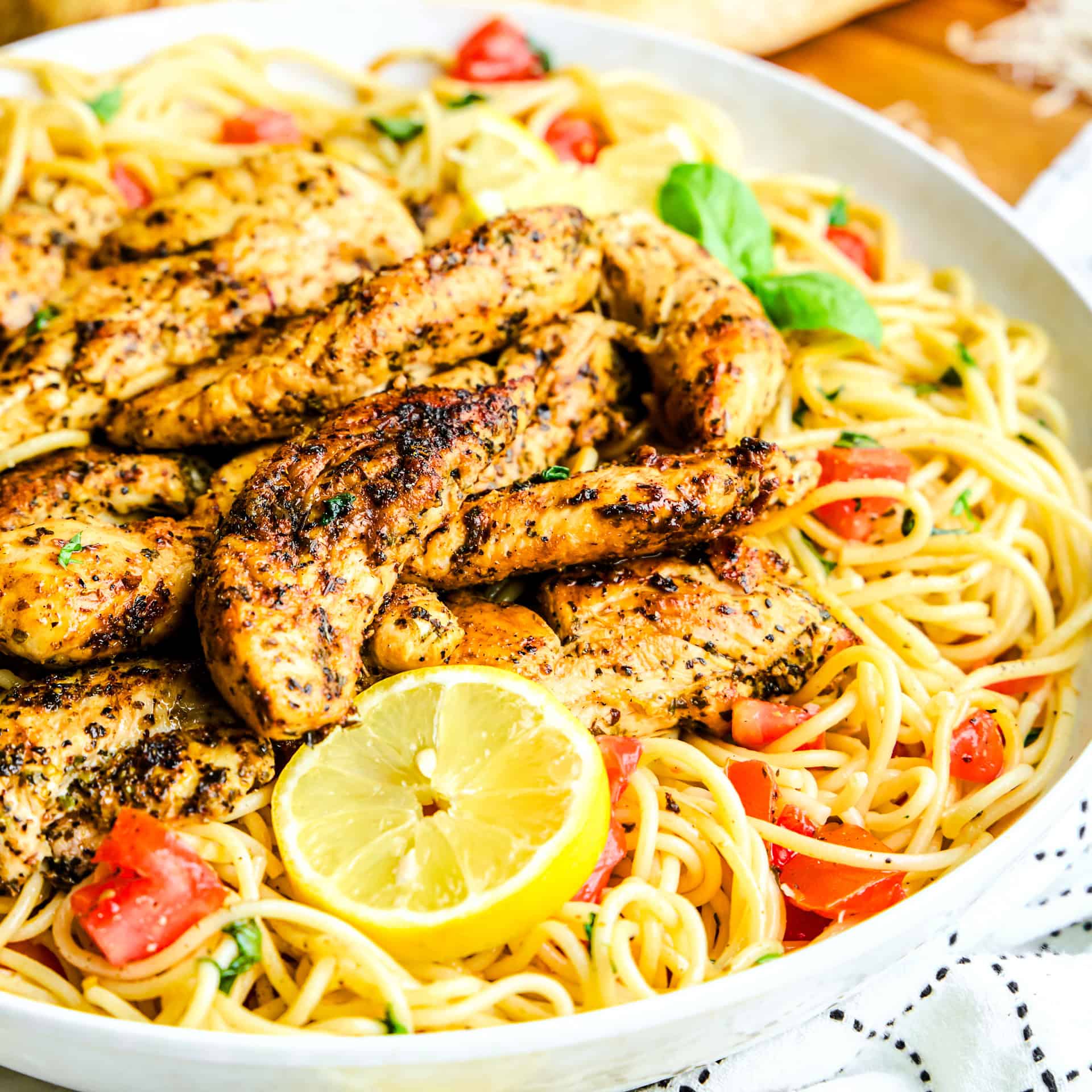 Lemon Herb Chicken Spaghetti in a large bowl with tomatoes and basil.
