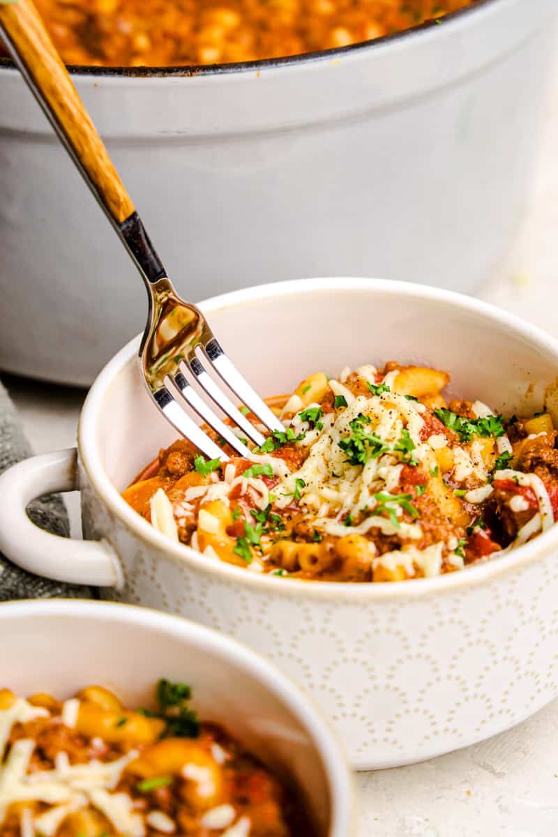 Old Fashioned American Goulash in a white bowl with a fork.